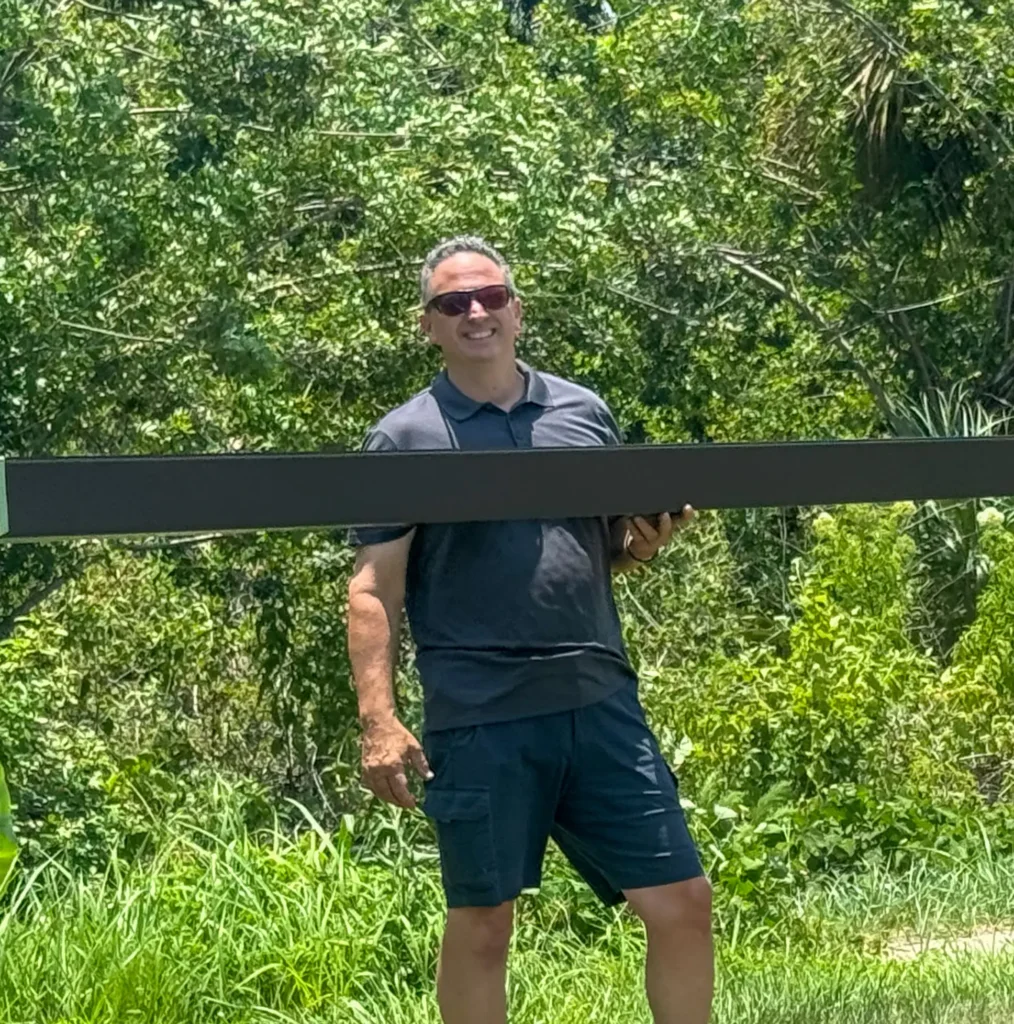 Sal holding black gutter at an on site install with green grass and trees